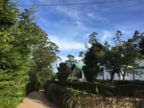 a house with a stone wall next to a street at The Trevene Hotel in Nuwara Eliya