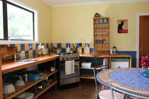 a kitchen with a stove and a sink and a table at Kahurangi Cottage Wilderness Retreat in Stanley Brook