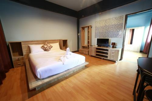Un dormitorio con una gran cama blanca y un televisor. en M Place, en Ban Kao
