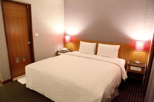 a hotel room with a large white bed with two lamps at Beauty Hotels Taipei - Hotel Bchic in Taipei