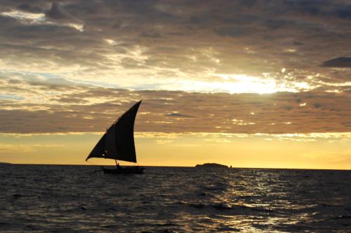 a sail boat in the ocean at sunset at Remo e Berenice in Nosy Komba