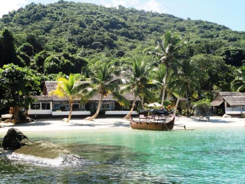 a boat on the shore of a beach with palm trees at Remo e Berenice in Nosy Komba