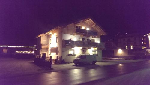 a white building with a balcony at night at Gästehaus die geislerin in Gerlos
