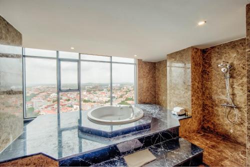 a bathroom with a tub and a shower with a window at Muong Thanh Luxury Bac Ninh Hotel in Bắc Ninh