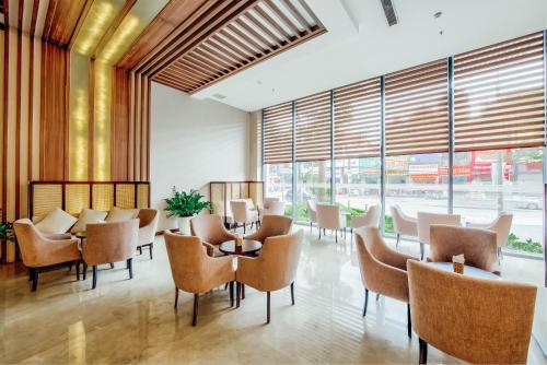 a restaurant with tables and chairs and large windows at Muong Thanh Luxury Bac Ninh Hotel in Bắc Ninh