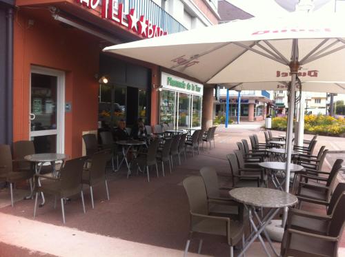 an outdoor patio with tables and chairs and an umbrella at Hôtel Bar le Globe in Saint Die