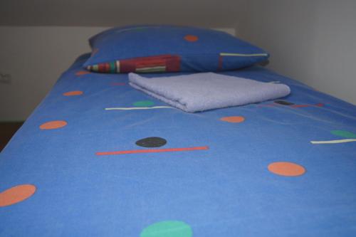 a bed with a blue bedspread with orange polka dots at Pokoje Gościnne "U Karola" Pracownicze in Ścinawa