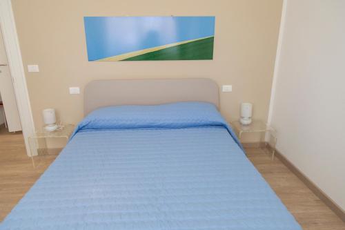 a bedroom with a blue bed with a painting on the wall at Casa Prima Fila Mare in Porto San Giorgio