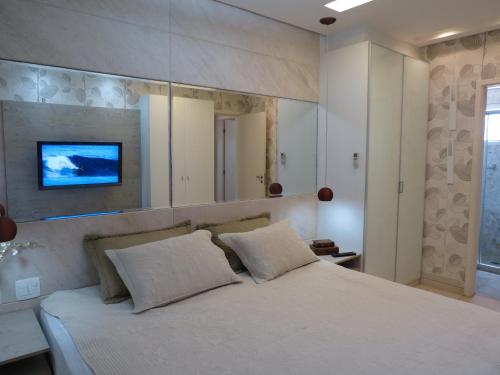 1 dormitorio con 1 cama blanca grande y espejo grande en Conforto e Lazer na Frente do Mar ao Lado do Beach Park, en Aquiraz