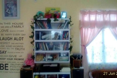 a book shelf with books on it next to a window at D-Rima Homestay Ruteng in Ruteng