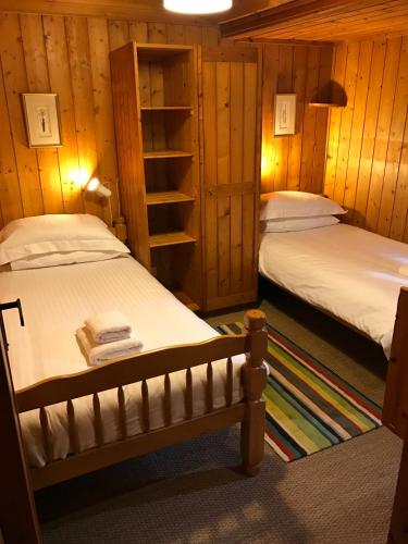 two beds in a room with wooden walls at Loch Monzievaird Chalets in Crieff