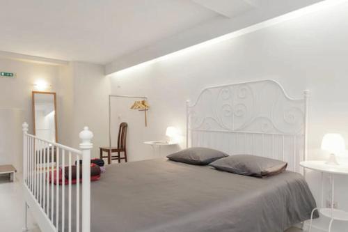 a white bedroom with a large bed and a staircase at House Cedofeita in Porto