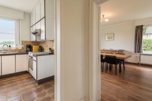 a kitchen with white cabinets and a table with chairs at Holiday home Zelenachten in Zele