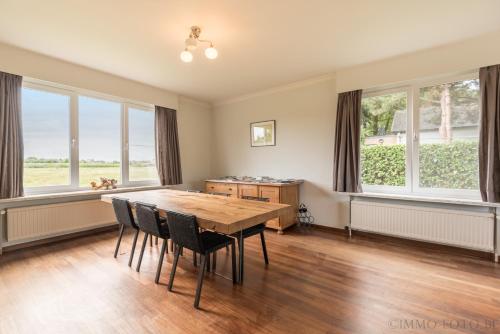 a dining room with a table and chairs and windows at Holiday home Zelenachten in Zele