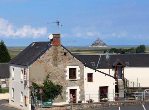 an old brick building with a hill in the background at Aux Chambres du Mont in Huisnes-sur-Mer