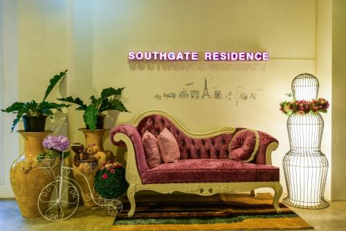 a living room with a red couch and some plants at Southgate Residence Hotel - SHA Certified in Chumphon