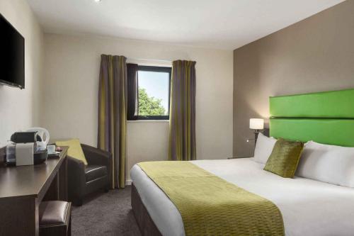 a hotel room with a bed and a desk and a window at Ramada Birmingham Oldbury M5 J2 in Oldbury