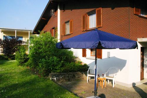 a blue umbrella and two chairs and a table at Haus Nussbaumweg 6 in Giswil