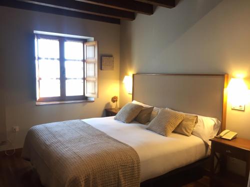 - une chambre avec un grand lit et une fenêtre dans l'établissement El Coto Hotel Restaurante, à Vitoria-Gasteiz