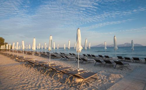 a row of umbrellas and chairs on a beach at Caravia Beach Hotel in Marmari