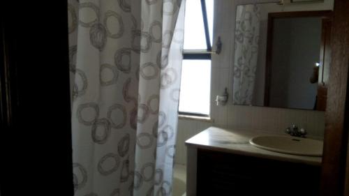 baño con lavabo y cortina de ducha en Mónaco Apartment, en Armação de Pêra