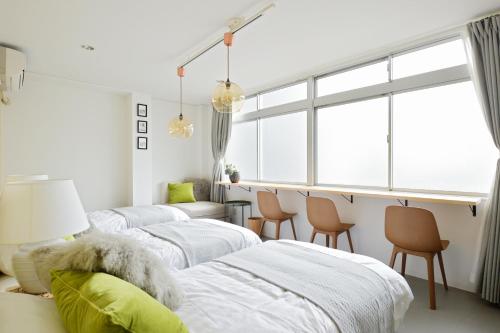three beds in a room with chairs and a window at nid Osaka TENNOJI in Osaka