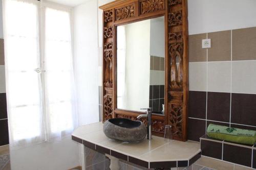 a bathroom with a large mirror and a stone sink at Les Chambres du Clos des Capucins in Barjac