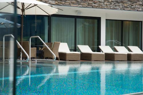 a swimming pool with lounge chairs and an umbrella at Hotel Goldried in Matrei in Osttirol