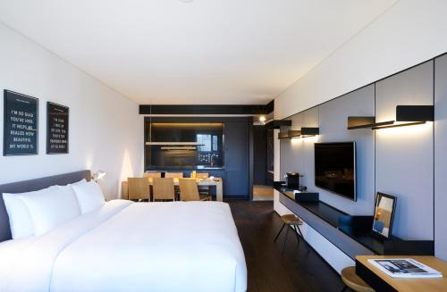 a bedroom with a large bed and a desk with a tv at GLAD Yeouido in Seoul