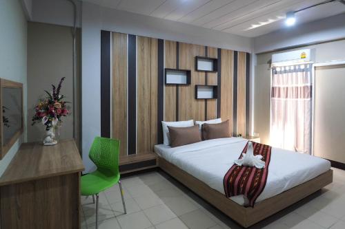 a bedroom with a bed and a desk and a green chair at Supreme Place SHA Plus in Khon Kaen