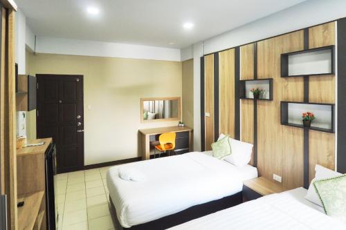 a hotel room with two beds and a television at Supreme Place SHA Plus in Khon Kaen