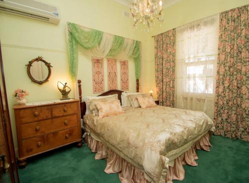 a bedroom with a bed and a dresser and a window at Ella's Place in Broken Hill