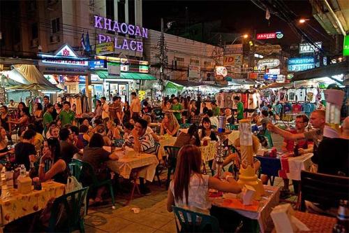 a crowd of people sitting at tables in a market at night at Baan Pinklao in Bangkok