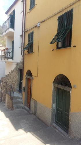 a yellow building with green doors on a street at La Terrazza Sul Blu in Corniglia