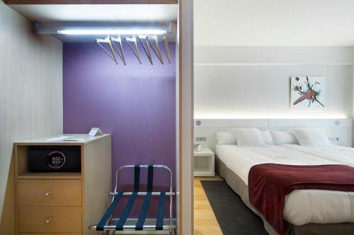 a bedroom with a bed and a purple wall at Sercotel Ciudad de Miranda in Miranda de Ebro