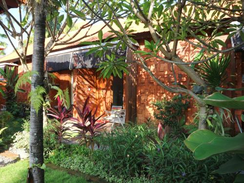 a wooden house with a garden in front of it at Louto Dmell Villa & Guesthouse in Sanur