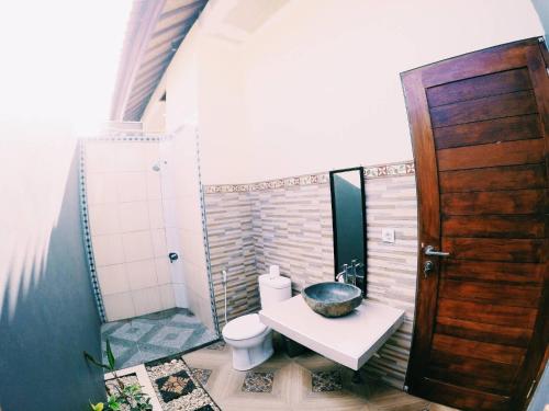 bagno con servizi igienici, lavandino e porta in legno di Pandawa Lembongan Homestay a Nusa Lembongan