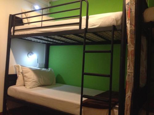a room with two bunk beds with a green wall at Woodpecker Lodge, Kuching in Kuching
