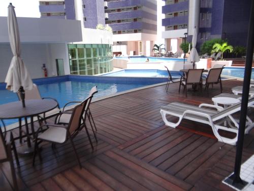 una terraza con sillas, una mesa y una piscina en Beach Class Fortaleza, en Fortaleza