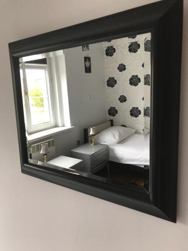 espejo que refleja un dormitorio con cama y ventana en Villa Romeo, en Brzeg