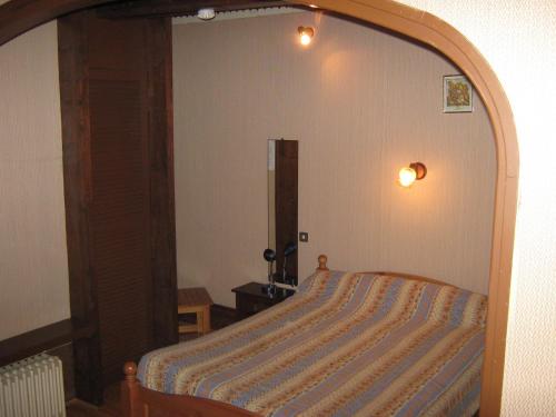 a bedroom with a bed with a striped blanket at Logis Hotel Restaurant La Chaumière in Tournon-sur-Rhône