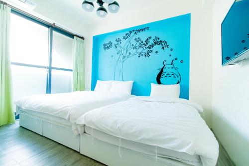 a bedroom with two beds and a blue wall at Lè mù in Taichung