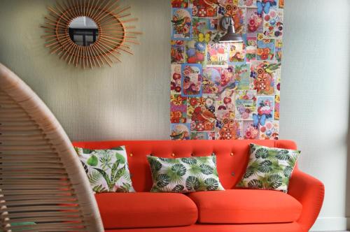 an orange couch in a living room with a mirror at Logis Boutique Hotel Novalis in Gradignan