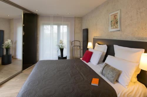 um quarto com uma cama grande com almofadas brancas e vermelhas em Le Petit Coq aux Champs - Teritoria em Campigny