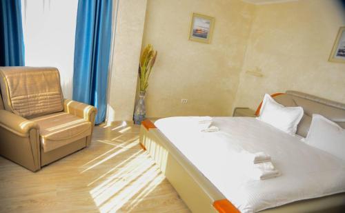 a hotel room with a bed and a chair at La Marcu Pensiune in Tulcea