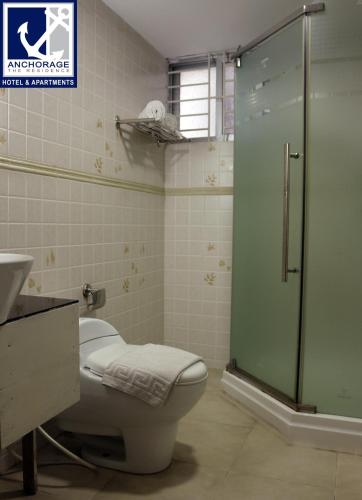 a bathroom with a toilet and a glass shower at Anchorage The Residence in Dhaka
