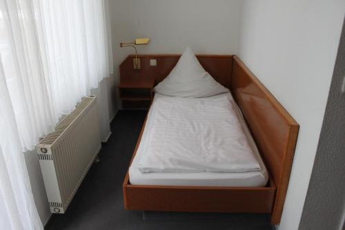 a small bed in a room next to a window at Hotel Roemerstein in Mainz