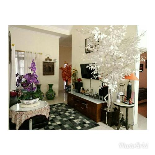 uma sala de estar com televisão e uma mesa com flores em Guest House Abimanyu em Kaliurang