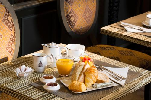 - un plateau de petit-déjeuner composé de croissants et de jus d'orange sur une table dans l'établissement Hôtel des Grands Hommes, à Paris