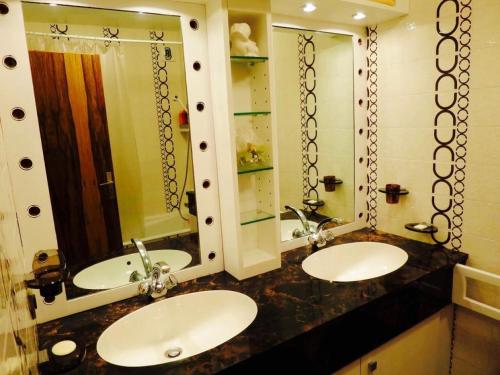 a bathroom with two sinks and two mirrors at Domaine du Jardin Alpin in Courchevel